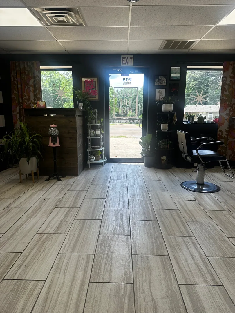 Dark, warm salon interior with plants and styling chair